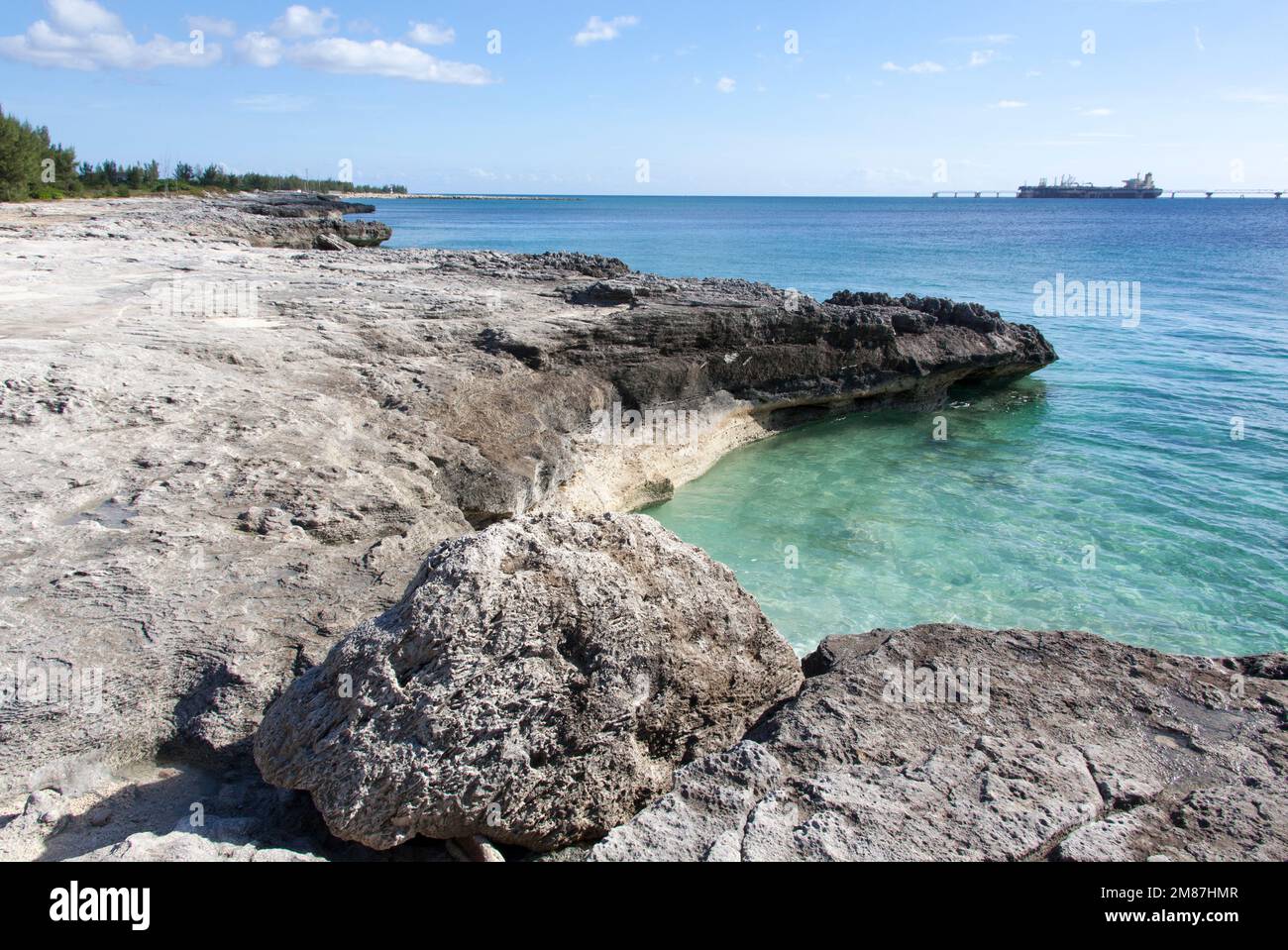 La vista panoramica della costa rocciosa erosa dell'isola di Grand Bahama e di una nave industriale ormeggiata nel molo umido. Foto Stock
