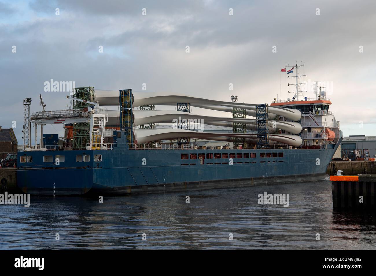 Pale di turbine eoliche a bordo di una nave da carico in un piccolo porto costiero Foto Stock