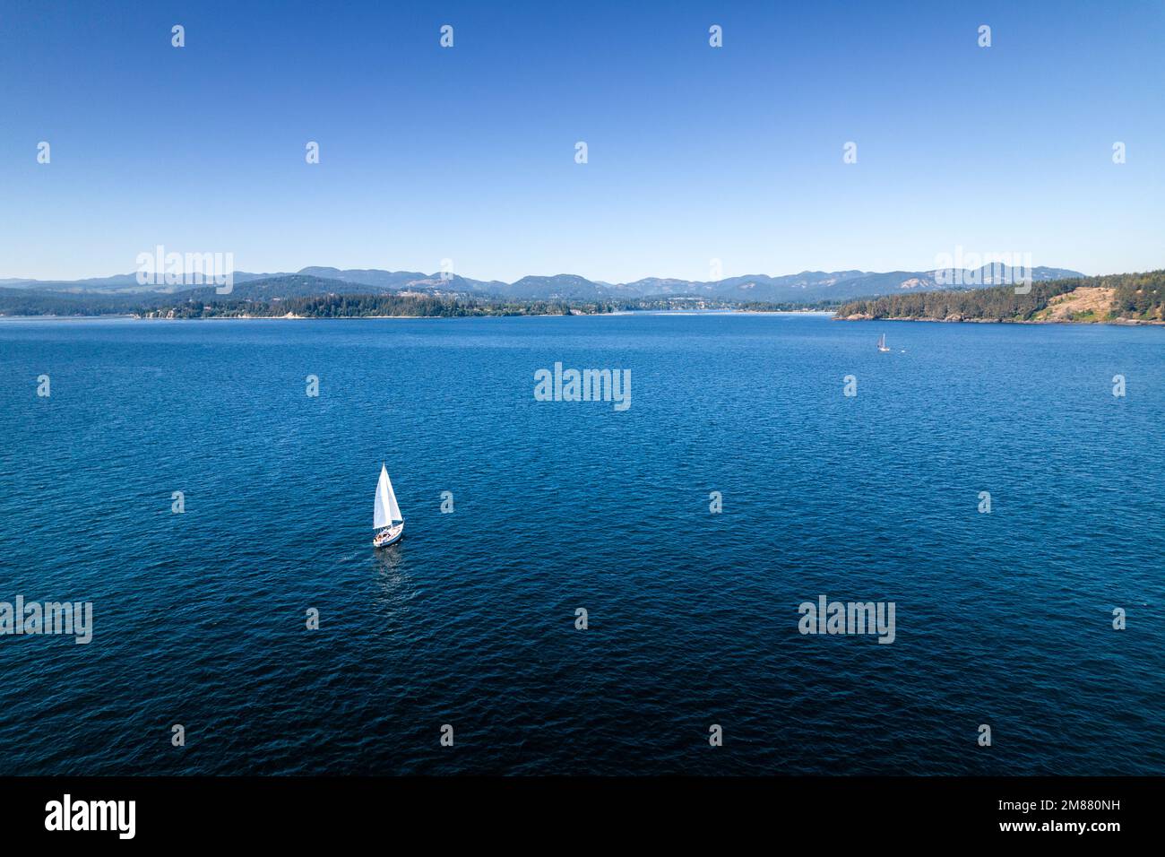 Barca a vela vicino alla costa, riprese aeree di droni, Isola di Vancouver, Sooke BC, oceano di giorno soleggiato. Foto Stock