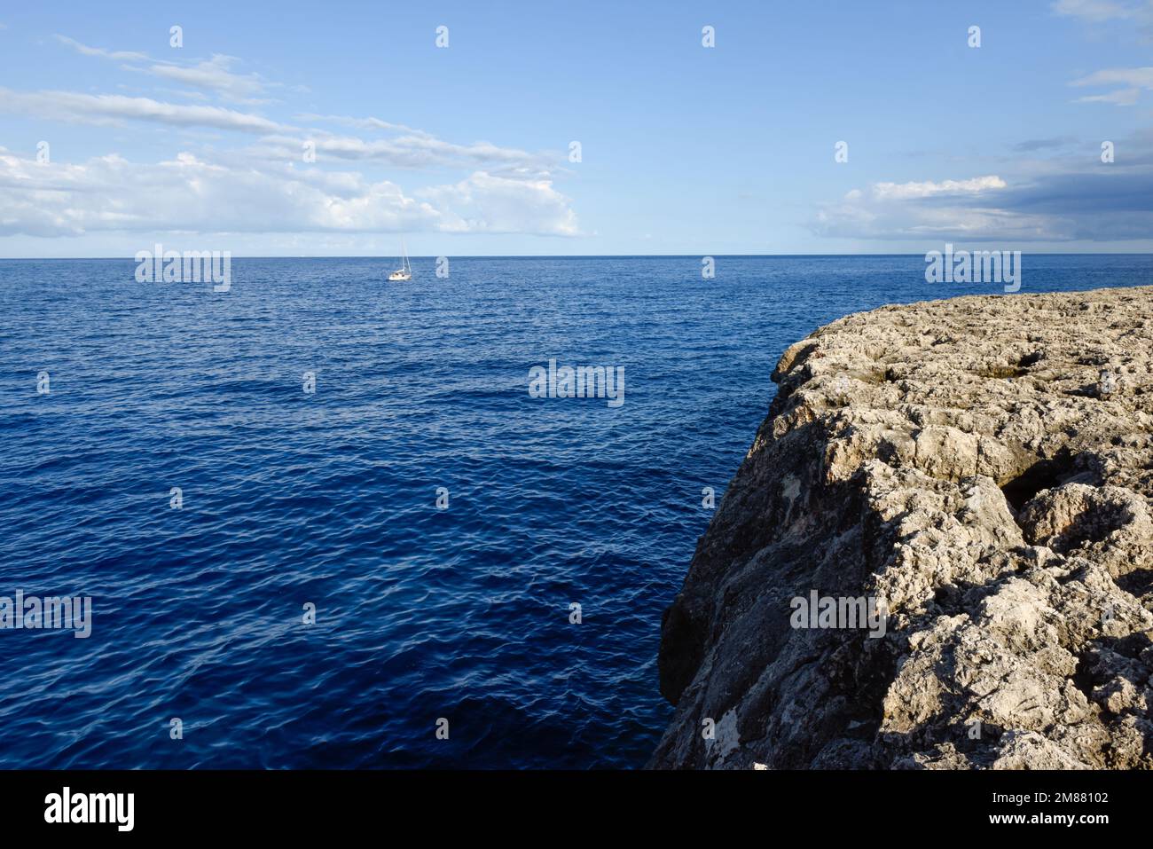 Vista sull'oceano da una scogliera mentre una barca naviga in lontananza Foto Stock