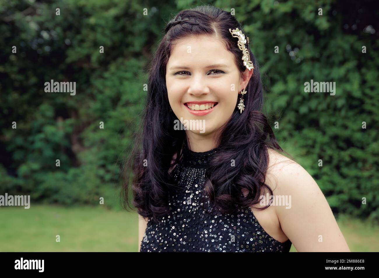 Primo piano di ragazza giovane sorridente in abito da corsa nero sequin Foto Stock