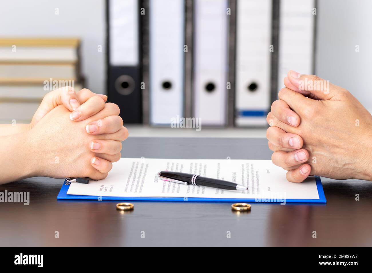 Mani di moglie e marito che firmano i documenti di divorzio o l'accordo preliminare all'ufficio dell'avvocato Foto Stock