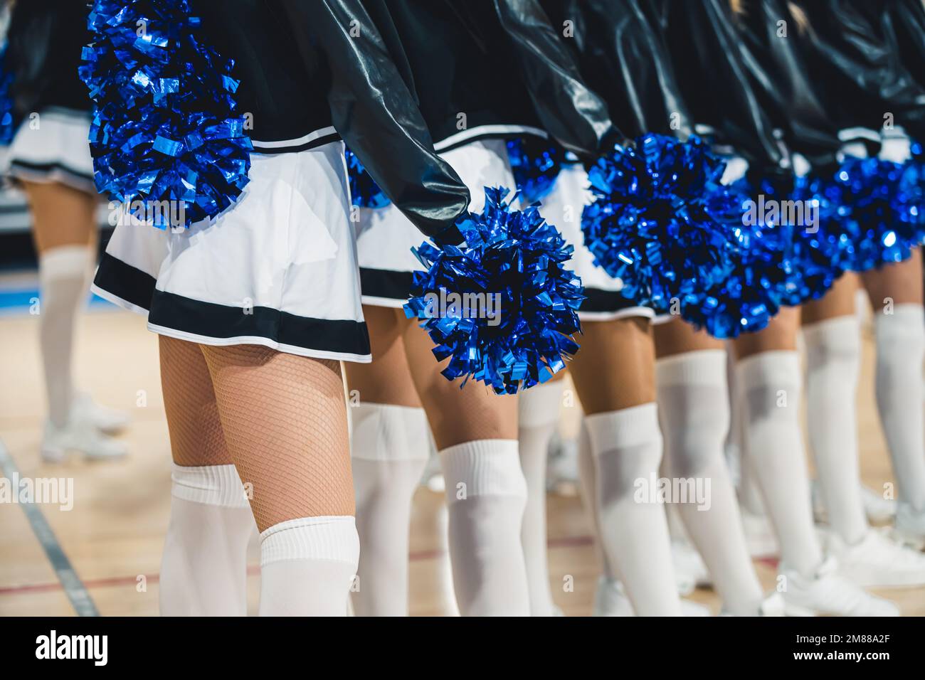 Cheerleaders dinamici in calzini bianchi che tengono pom pom pom mostrando spirito di squadra. Foto di alta qualità Foto Stock