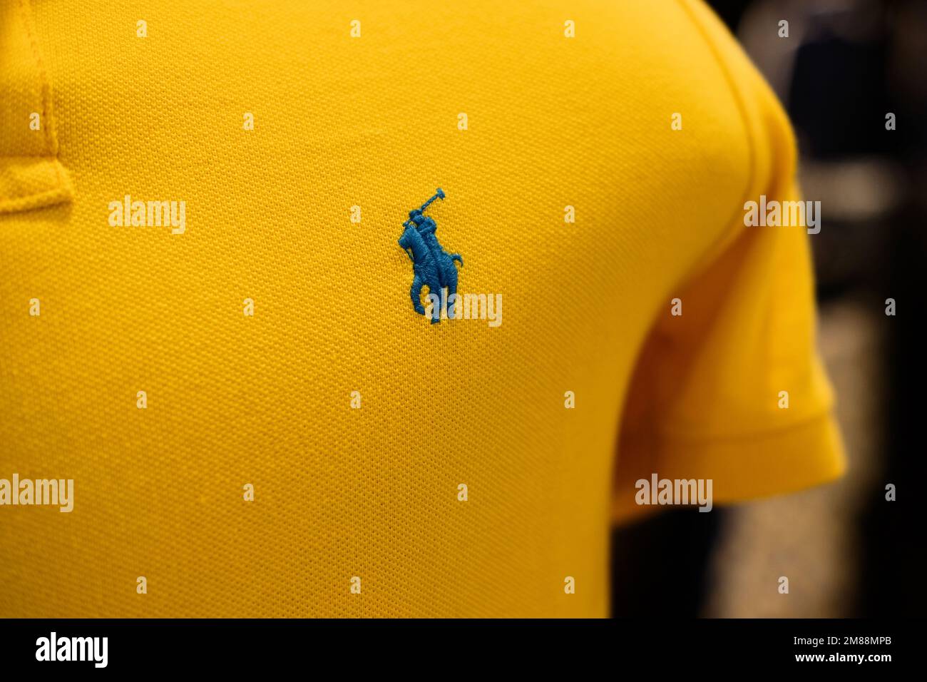 Polo Ralph Lauren ricamato con logo designer sul petto; polo gialla con logo blu. Foto Stock