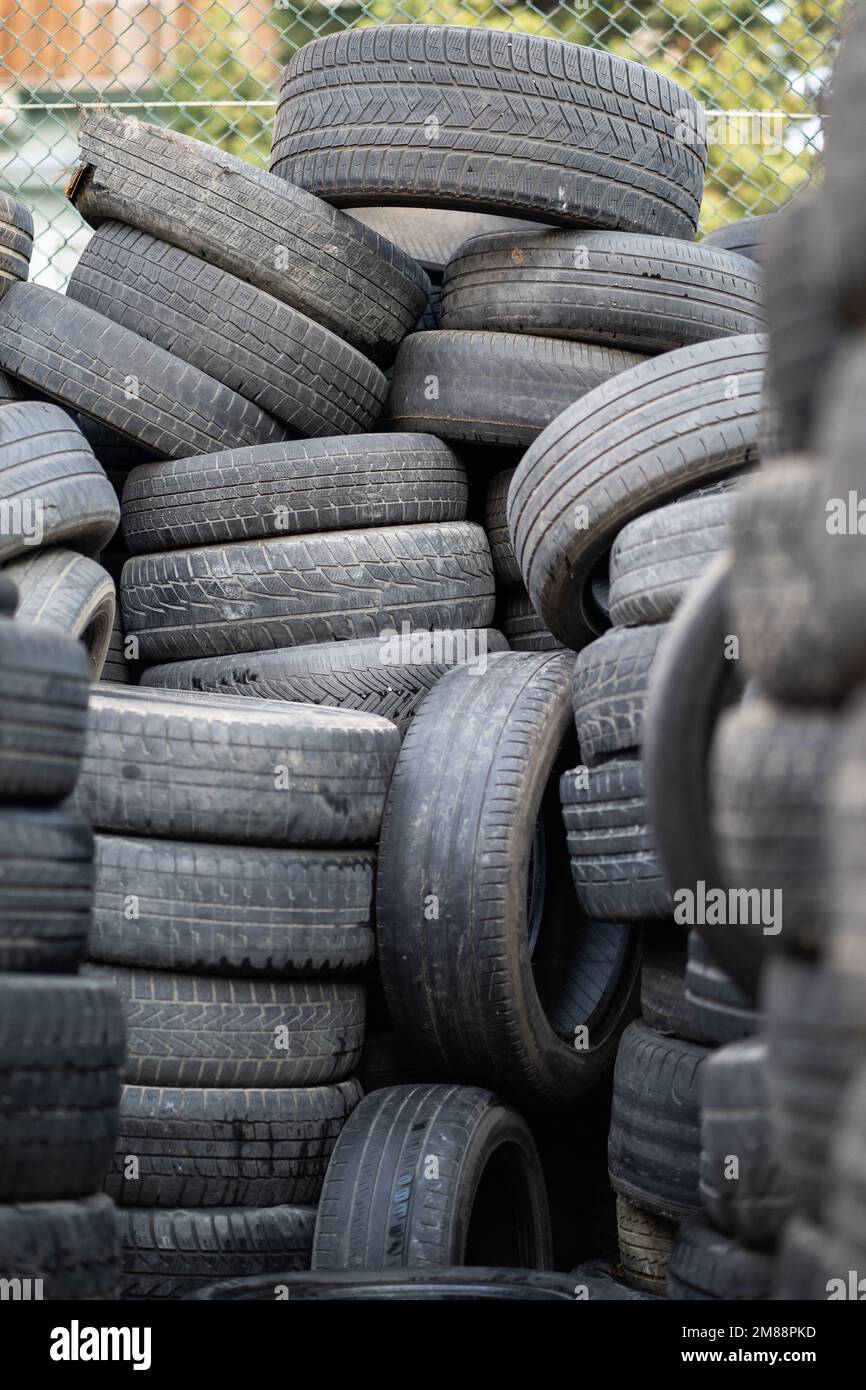 Vecchi pneumatici di gomma usati impilati con pali alti. Rifiuti pericolosi  che richiedono il riciclaggio e lo smaltimento Foto stock - Alamy