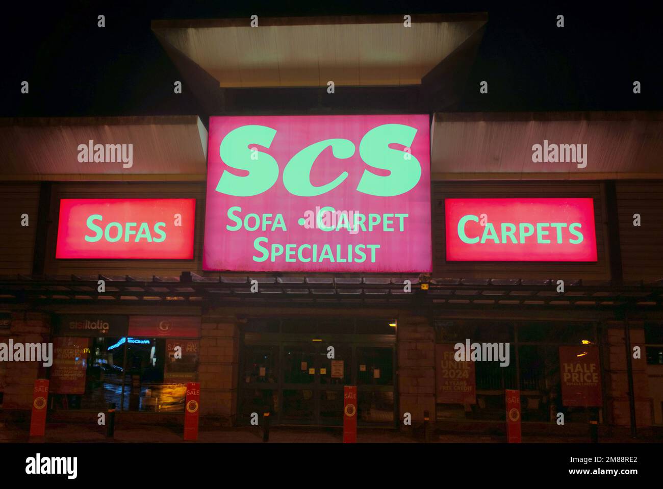 SCS sofa carpet Specialists Shop segno sopra l'entrata frontale di notte senza persone Great Western Retail Park1 Allerdyce Rd, Glasgow G15 6RX Foto Stock