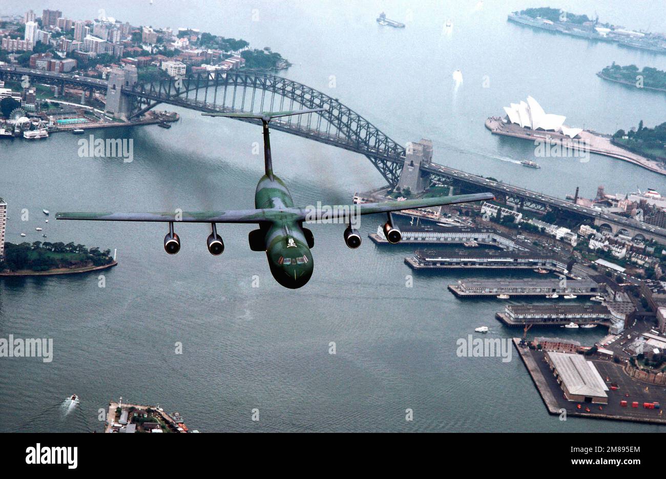 Un aereo Starlifter C-141b dell'aviazione militare US Air Force della 445th, Norton AFB, California, si illumina sul Sydney Harobar Bridge, Sydney Australia. Base: Sydney Harbor Stato: Nuovo Galles del Sud Paese: Australia (AUS) Foto Stock