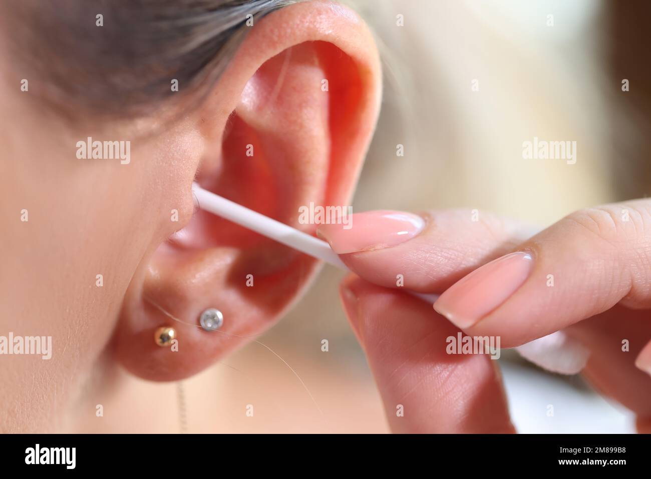 Primo piano delle donne pulisce l'orecchio con un bastoncino di cotone. Foto Stock