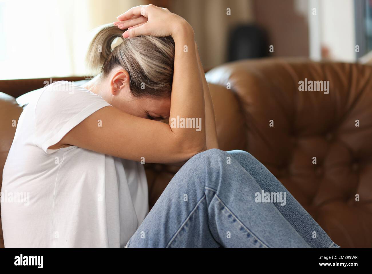 Depresso frustrata donna sente dolore, tristezza e stress perché molti problemi mentre si siede sul divano. Foto Stock