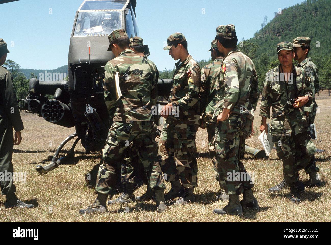 I soldati dell'Honduran del Battaglione artiglieria DEL 1st osservano come un elicottero AH-1 Cobra dalla Brigata della Cavalleria dell'aria del 17th è armato di missili e 20mm munizioni prima di una corsa di combattimento sul campo del Balomple Range. Il presidente Ronald Reagan ha mobilitato la task force statunitense Dragon/Golden Pheasant, composta sia dalla 82nd Airborne Division che dalla 7th Light Infantry Division, per scoraggiare le forze del Nicaragua dall'ingresso in Honduras. Subject Operation/Series: DRAGON/GOLDEN PHEASANT base: Zambrano Paese: Honduras (HND) Foto Stock