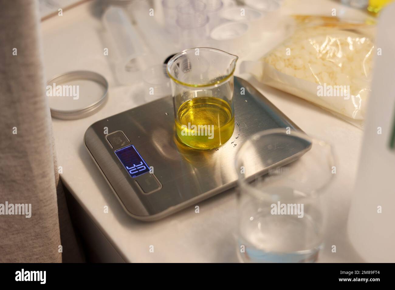 Pesare l'olio di jojoba nel becher sulla bilancia elettronica del laboratorio Foto Stock