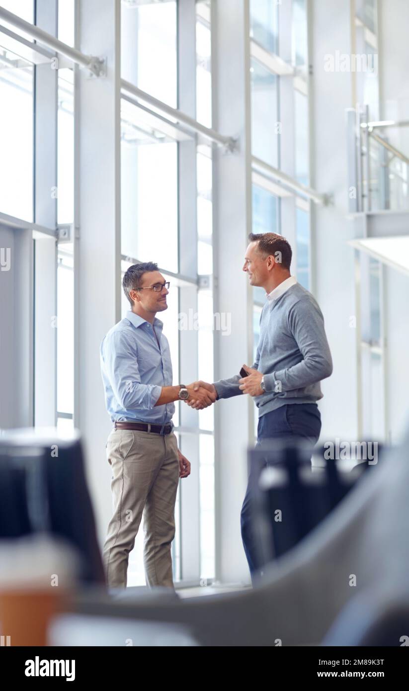 Uomini d'affari, stretta di mano o saluto nella hall dell'hotel, ufficio moderno o lounge dell'aeroporto in una riunione CRM. Sorridi, lavoratori felici o maturi che scuotono le mani Foto Stock