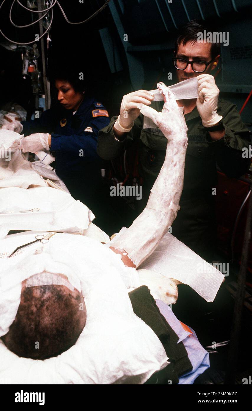 MAJ. Barba, un membro del 2nd Aeromedical evacuation Squadron, e MAJ Gilliam, un membro del personale del Wiesbaden Hospital, cambiare medicazioni per IL PICCOLO ufficiale 3rd Classe David Burbine. Il marinaio, che viene trasportato in Germania a bordo di un aereo militare Win g C-141b Starlift 438th per un ulteriore trattamento, è stato uno dei quattro crewmen en che sono stati gravemente feriti quando la fregata missilistica guidata USS SAMUEL B. ROBERTS (FFG-58) ha colpito una miniera mentre operava nel Golfo Persico. Paese: Sconosciuto Foto Stock