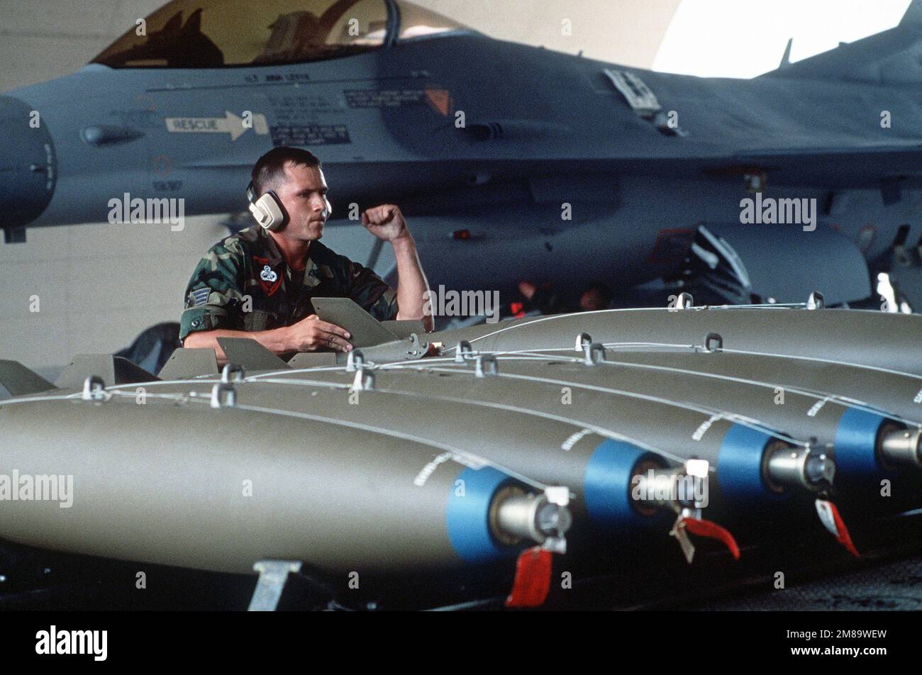 PERSONALE SGT. Adame Reveile segnala al conducente di un caricatore di armi di fermarsi mentre si preparano a caricare le bombe Mark 82 per uso generale su un F-16 Fighting Falcon Aircraft. Gli aerei partecipano al concorso di preparazione al combattimento Sabre Spirit '88, durante. Soggetto operativo/Serie: SABER SPIRIT '88 base: Osan Air base Paese: Repubblica di Corea (KOR) Foto Stock