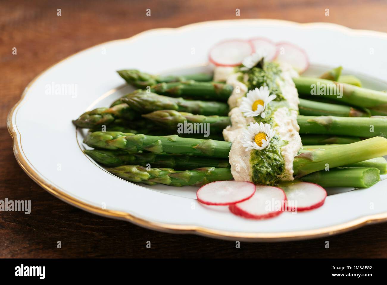 Asparagi con feta vegana e salsa di rucola, guarniti con ravanelli. Foto Stock