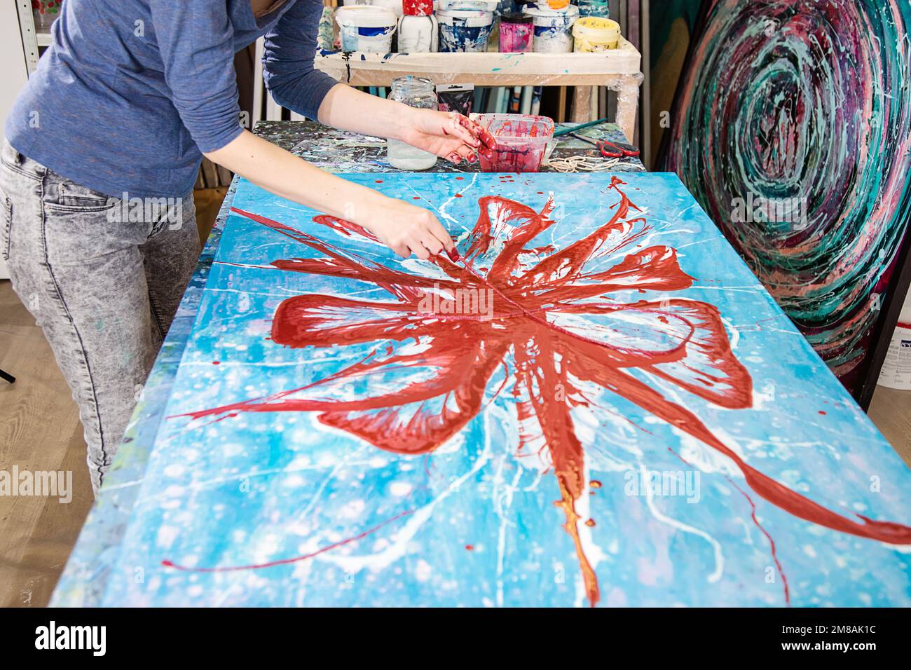 Foto ritagliata di mani di donna artista accatastata con pittura rossa con corda abstract immagine di fiore su tela. Foto Stock