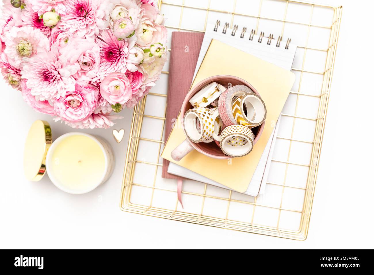 Desktop femminile con cartoleria in oro e rosa e fiori freschi Foto Stock