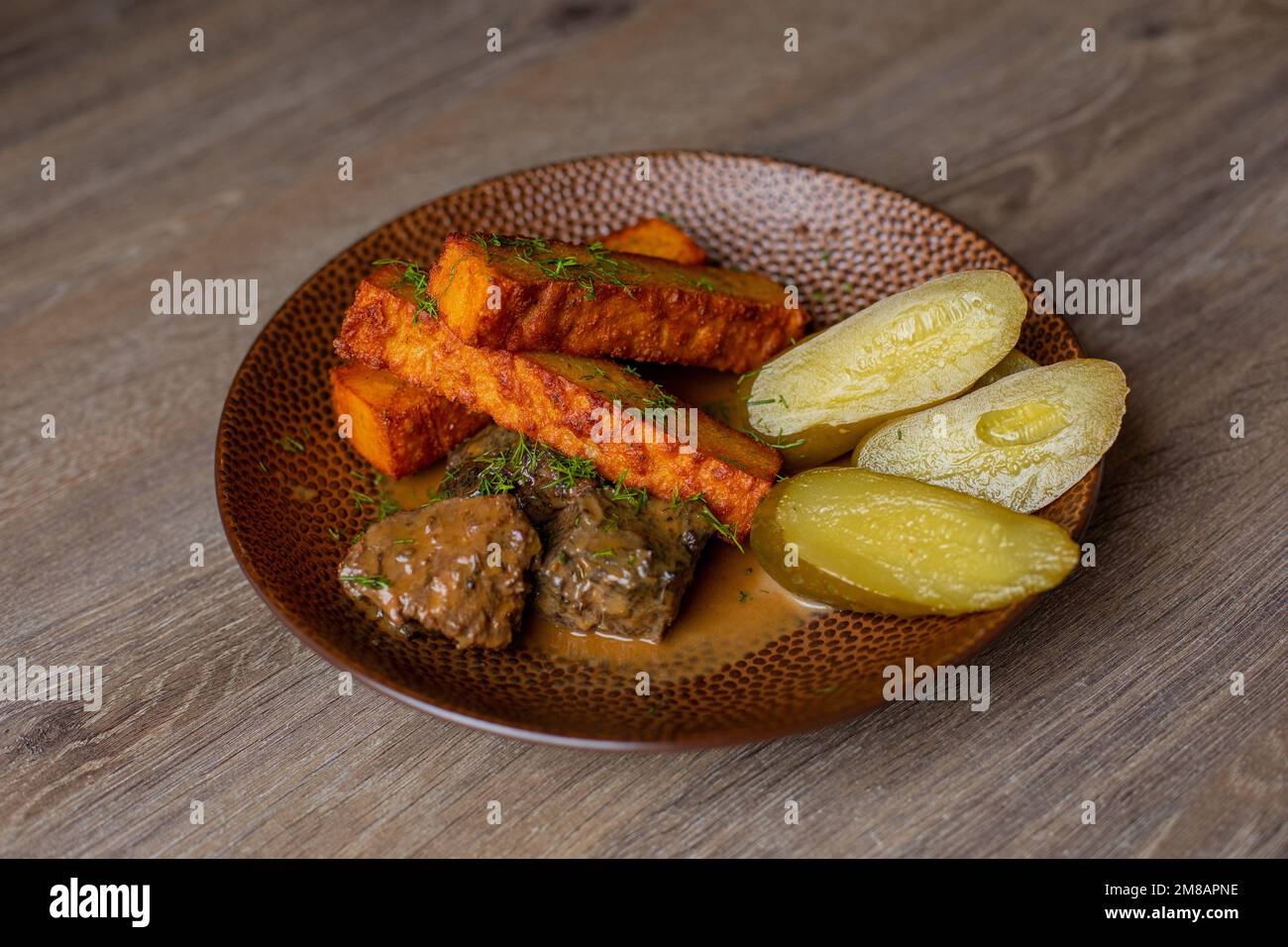 Primo piano del piatto con cetrioli sottaceto, bastoncini di formaggio fritti, pezzetti di carne di fegato fritto cosparso di aneto sul tavolo. Foto Stock