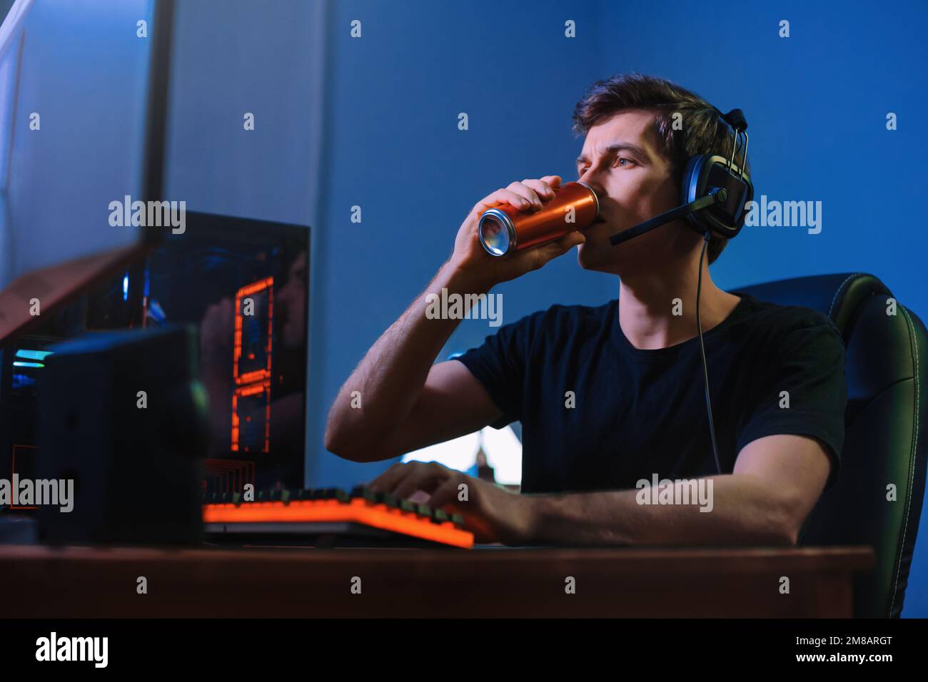 Cyber sport. Giocatori professionisti di cybersport allenarsi o giocare a videogame online sul suo PC a tarda notte, bere bevande energetiche di caffeina per concentrarsi, concentrarsi sul gioco. Gioco di squadra. Dipendenza da giochi Foto Stock