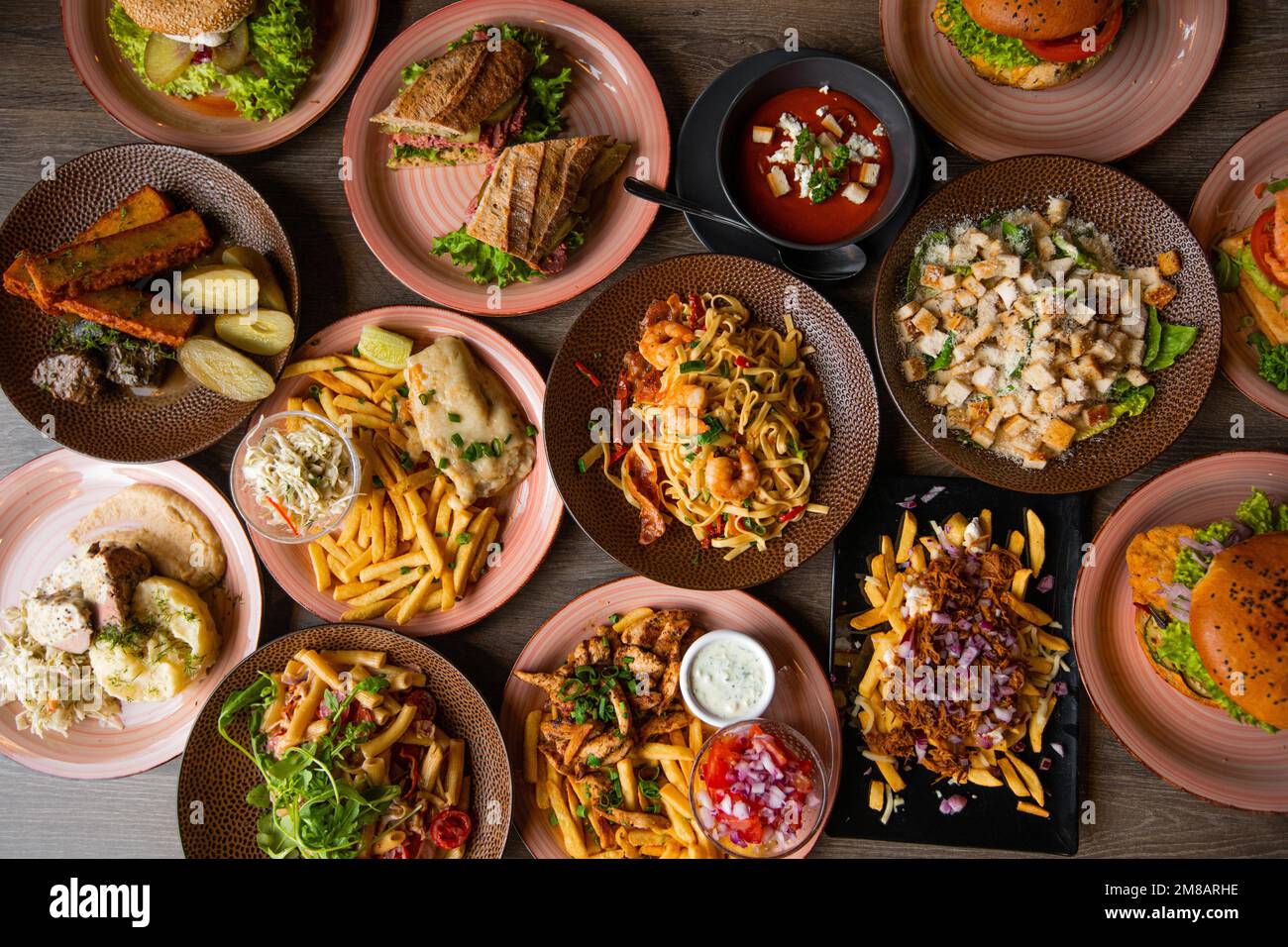 Vista dall'alto del cibo sul tavolo nella caffetteria. Pasta con gamberetti. Caesar insalata con crostini. Panini con lattuga. Zuppa di pomodoro. Foto Stock