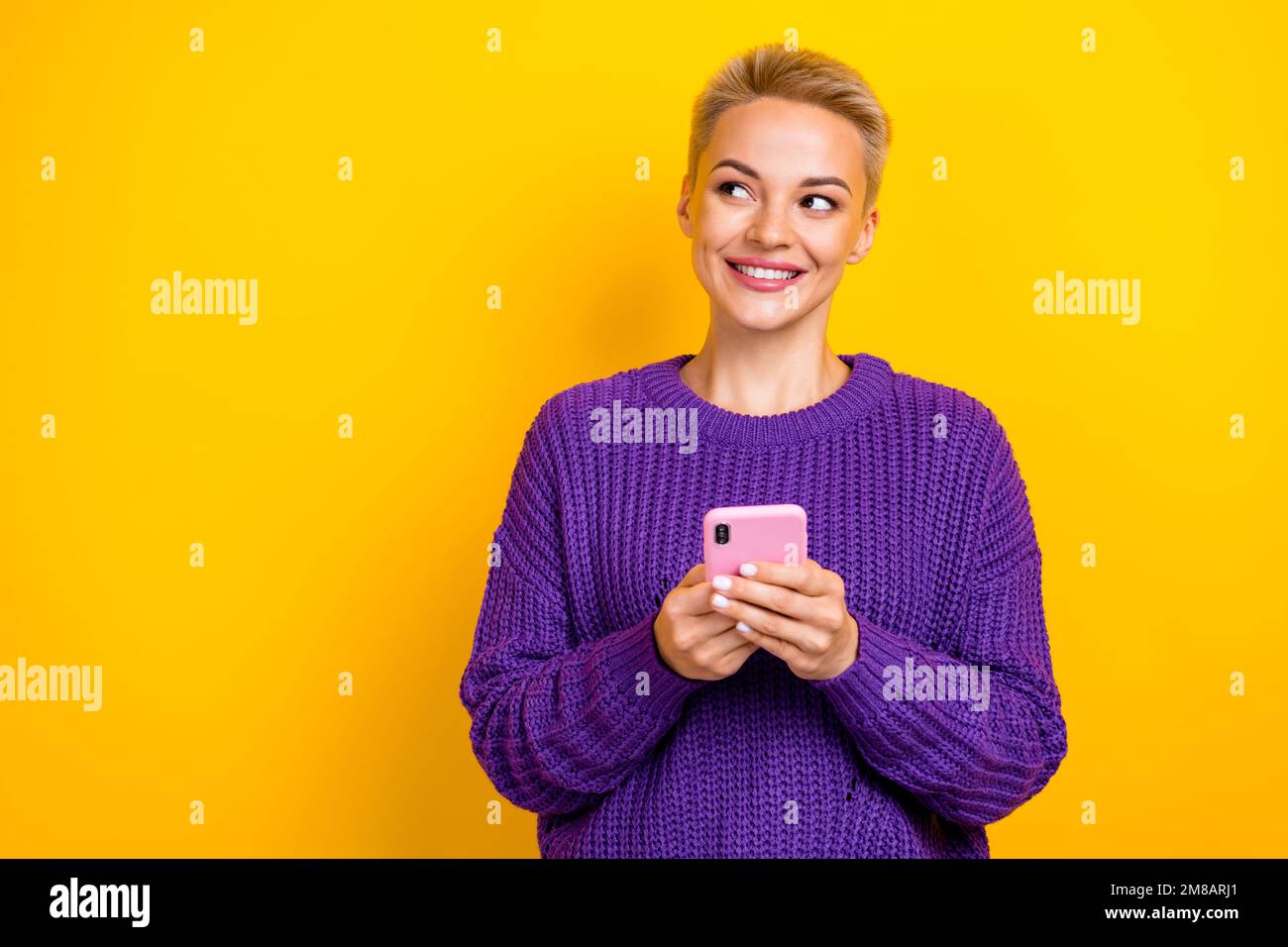 Foto ritratto di attraente blogger capelli biondo corto tenere telefono chatting sogno guardare vuoto spazio più seguaci isolati su sfondo giallo colore Foto Stock