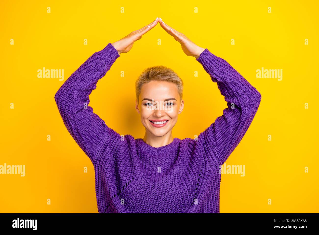 Foto di bella braccio donna positivo fare tetto sotto la testa sogno proprio appartamento ufficio centro città isolato su sfondo giallo Foto Stock