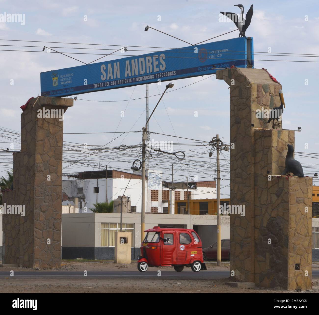 Un taxi rosso a tre ruote passa sotto un arco sopra la strada che forma una porta per San Andrés. Celebra la fauna locale: Guanay Cormoran (Leucocarb Foto Stock