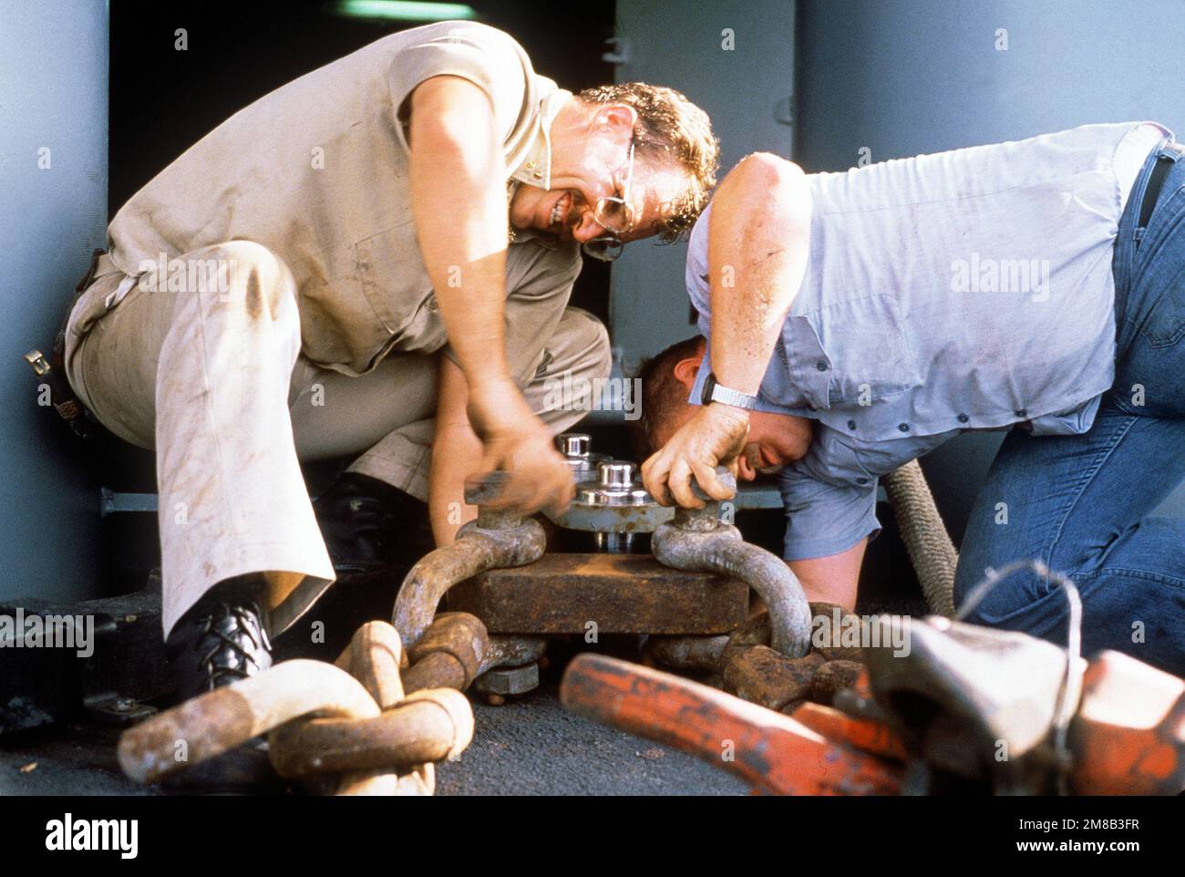 BOATSWAIN's Mate Davis e Boatswain's Mate 1st Class Greathouse attaccano gli anelli a vite a una piastra di rinforzo durante le operazioni di salvataggio per liberare il cacciatorpediniere USS SPRUANCE (DD-963). Lo SPRUANCE si è aggirato su Andros Island, Bahamas, 25 gennaio 1989. Paese: Oceano Atlantico (AOC) Foto Stock