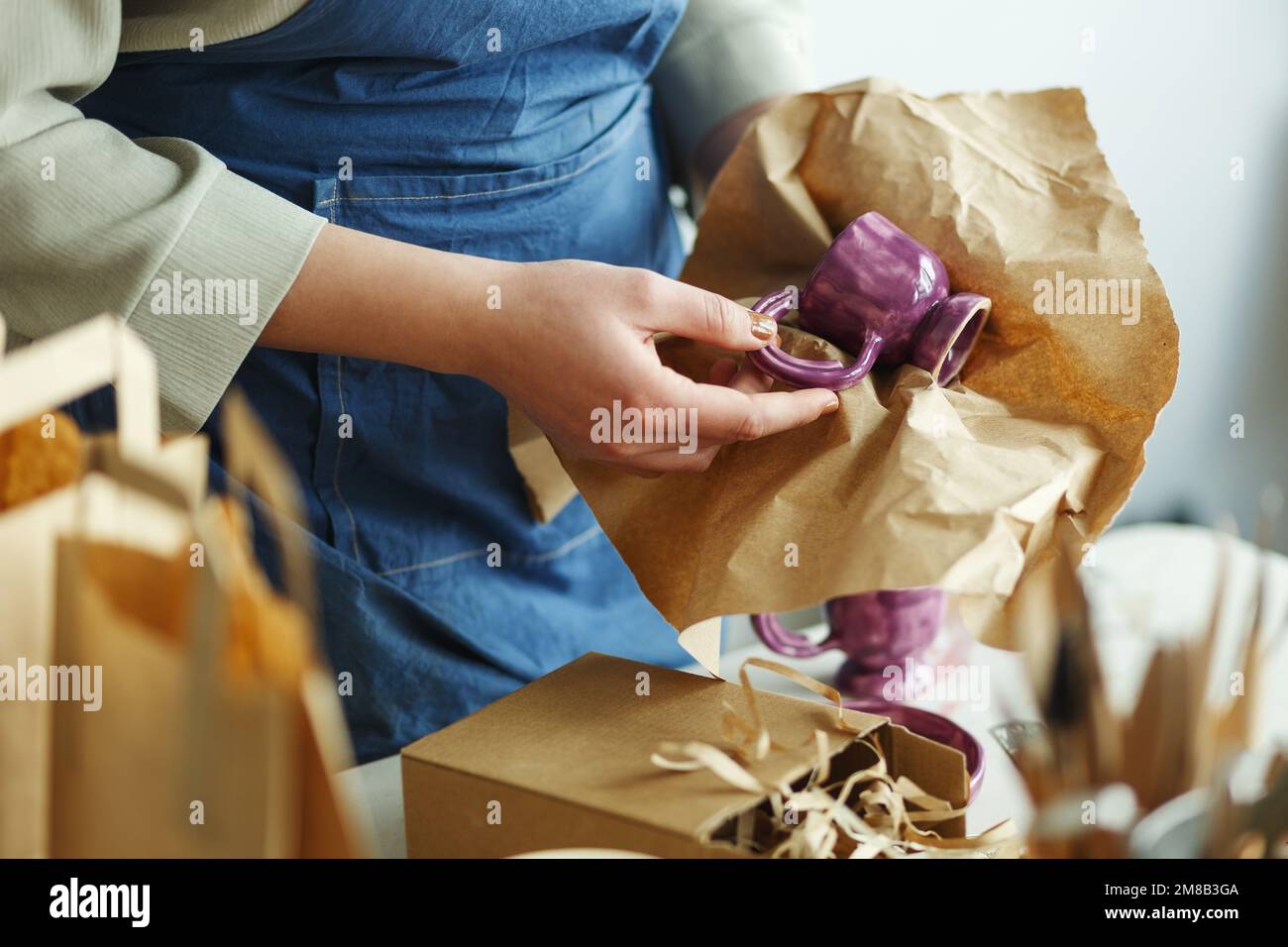Imprenditore donna irriconoscibile, impaccando una tazza di argilla viola. Imprenditore che lavora a casa con il suo prodotto in ceramica argilla. Vendita online busin Foto Stock