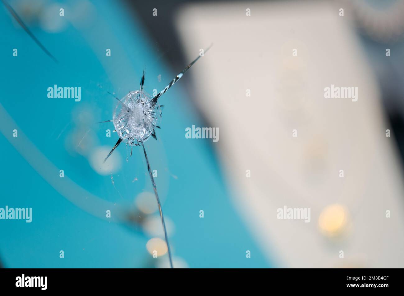 Particolare del foro trafitto nella vetrina del gioielliere rotta e frantumata dopo il tentativo di furto con gioielli sfocati in background in esposizione Foto Stock