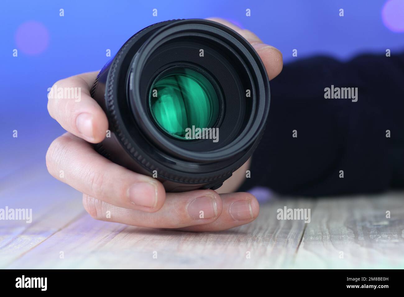 50mm lente in mano sul tavolo e sfondo blu Foto Stock