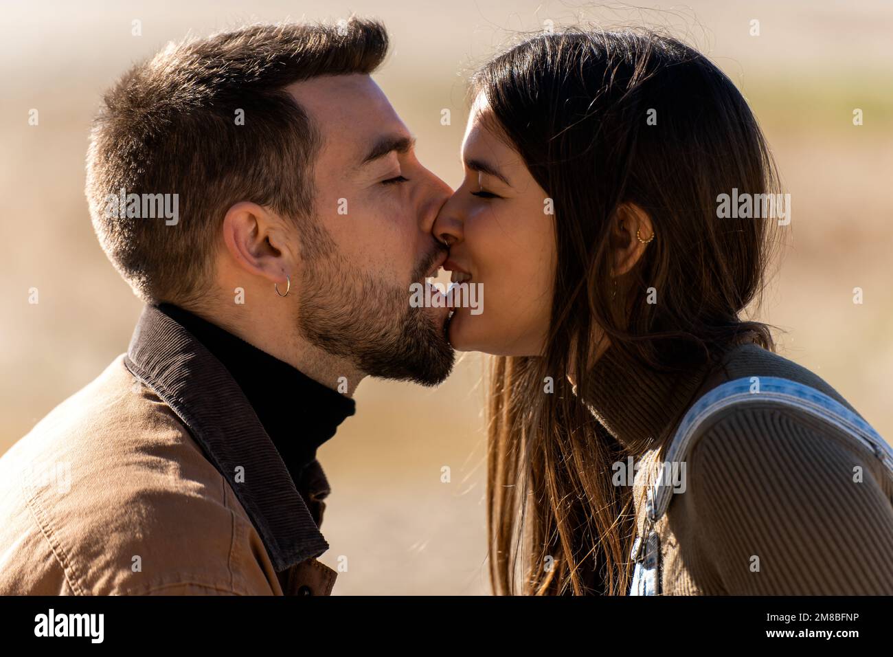 Giovane fidanzata e ragazza si baciano a occhi chiusi durante la festa di San Valentino il giorno di sole di giorno Foto Stock