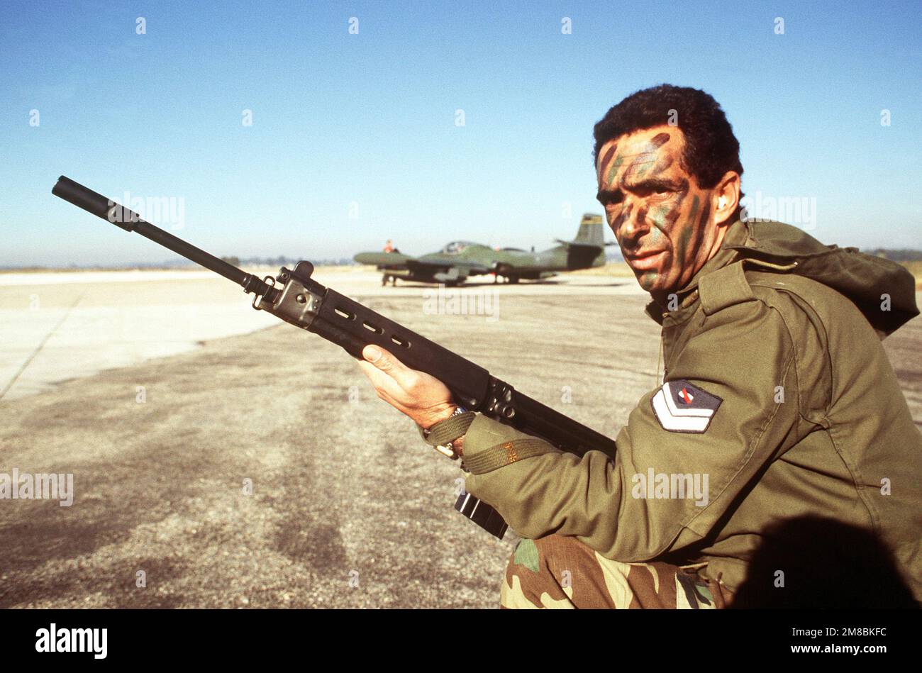 SGT Edwardo Agular, controllore d'aria tattico uruguayano, è a guardia di un 24th Tactical Air Support Squadron (24th TASS) OA-37 Dragonfly Aircraft durante un esercizio di addestramento tra il 24th TASS e i membri dell'aeronautica uruguayana. Agular è armato di un fucile FN FAL 7,62mm. Base: Durazno Nazione: Uruguay (URY) Foto Stock