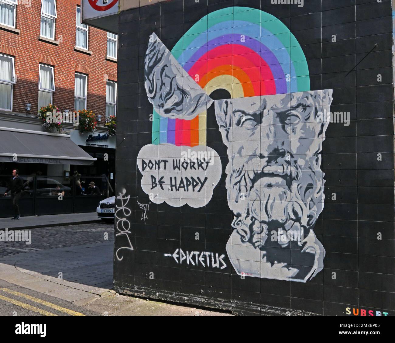 Non preoccupatevi, siate felici, una citazione di Epktetus, Epktetus, graffito su un muro di Dublino, arcobaleno che emerge dalla mente Foto Stock