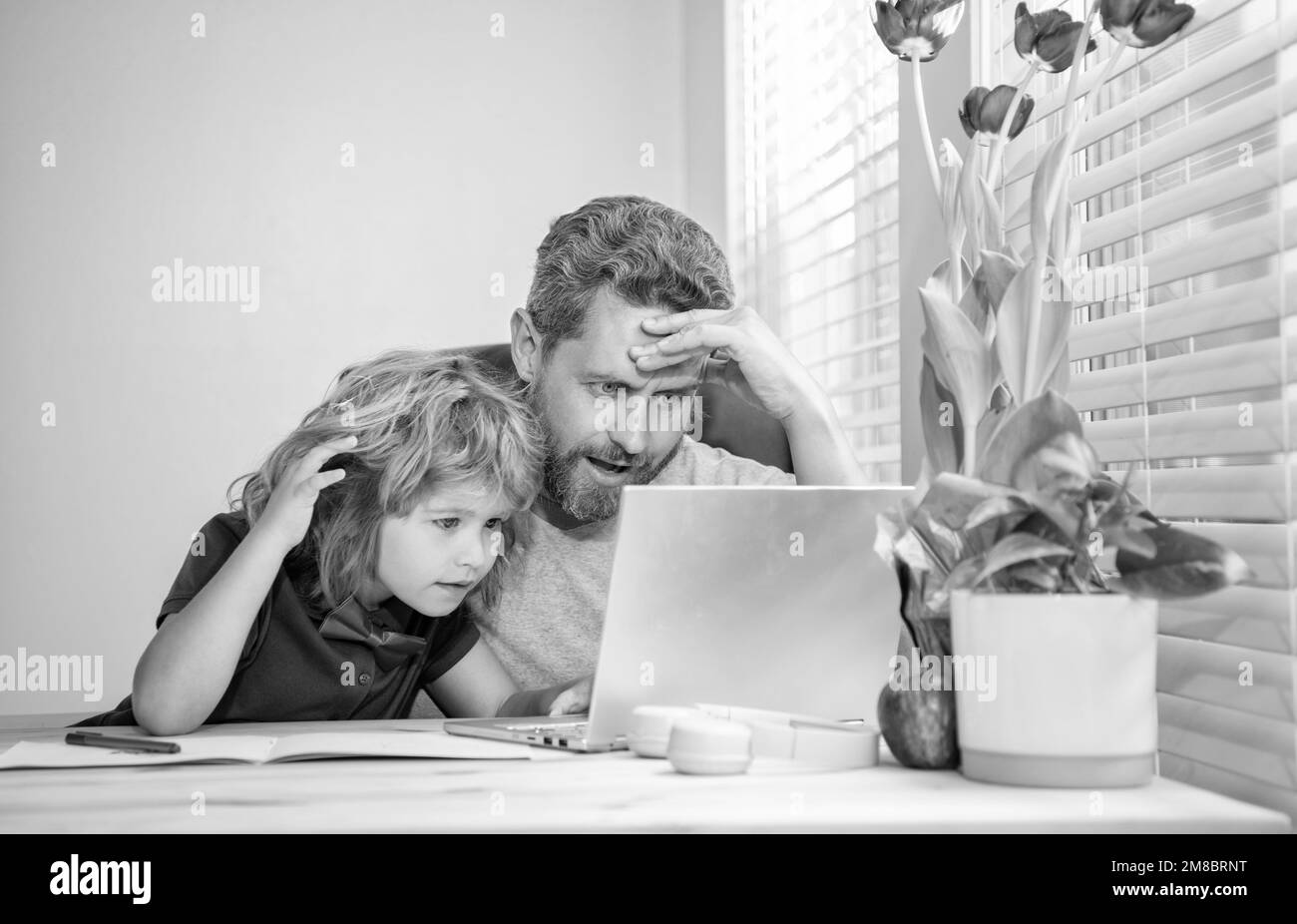 insegnante o papà uomo maturo che aiuta il figlio del bambino con i compiti a scuola sul computer, videoconferenza Foto Stock