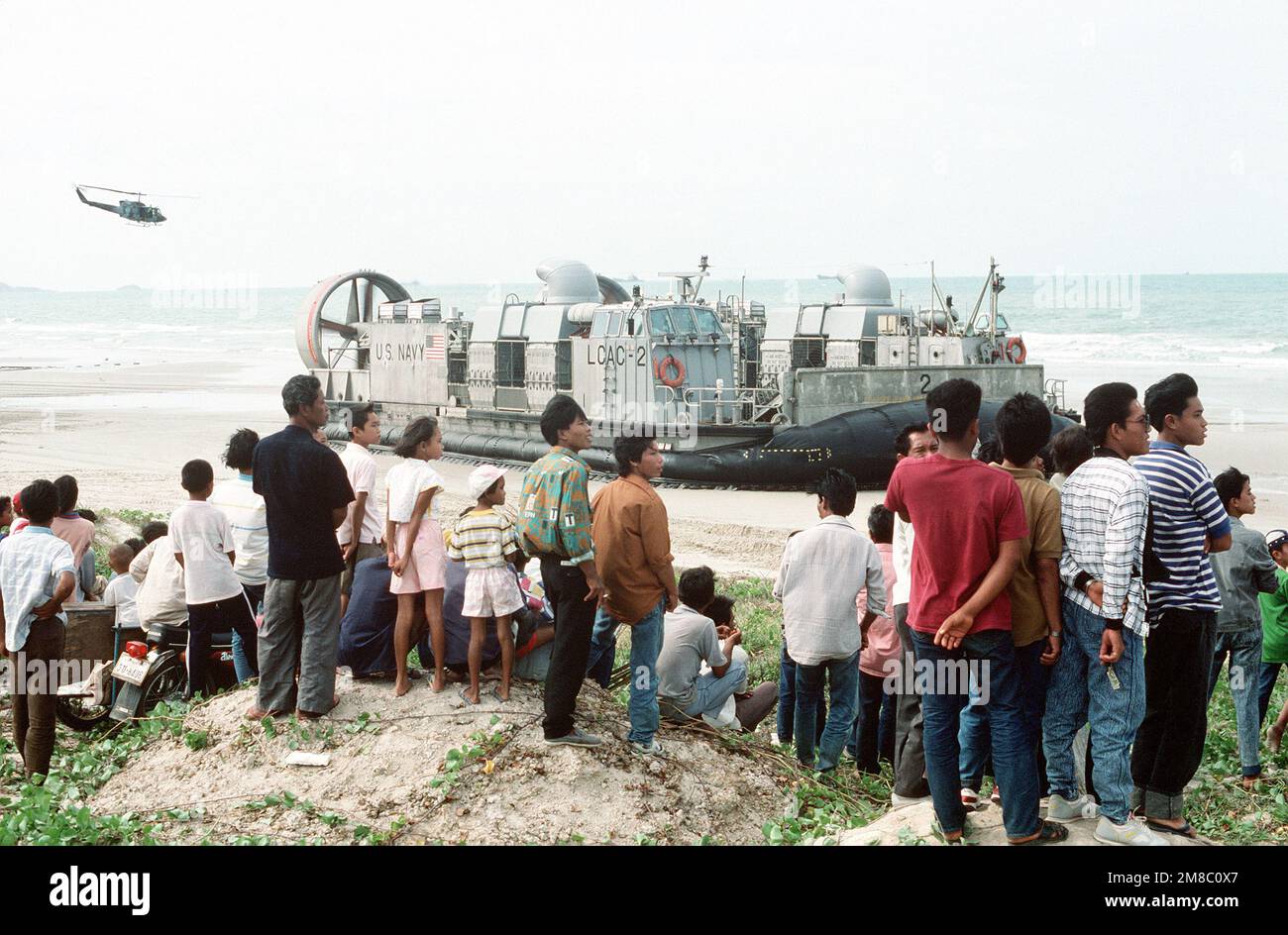I Thais locali osservano il velivolo di atterraggio del cuscino d'aria in barca LCAC2 durante la fase iniziale d'assalto dell'esercitazione congiunta thailandese/statunitense THALAY THAILANDESE '89. Subject Operation/Series: THALAY THAI '89 base: Pattaya Beach Paese: Thailandia (THA) Foto Stock