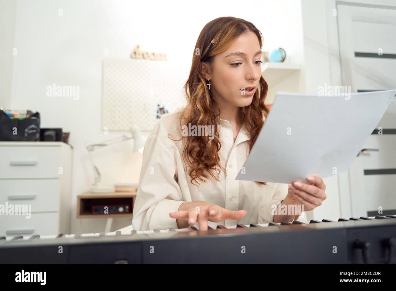 Compositore femminile concentrato che esegue composizione musicale su synth Foto Stock