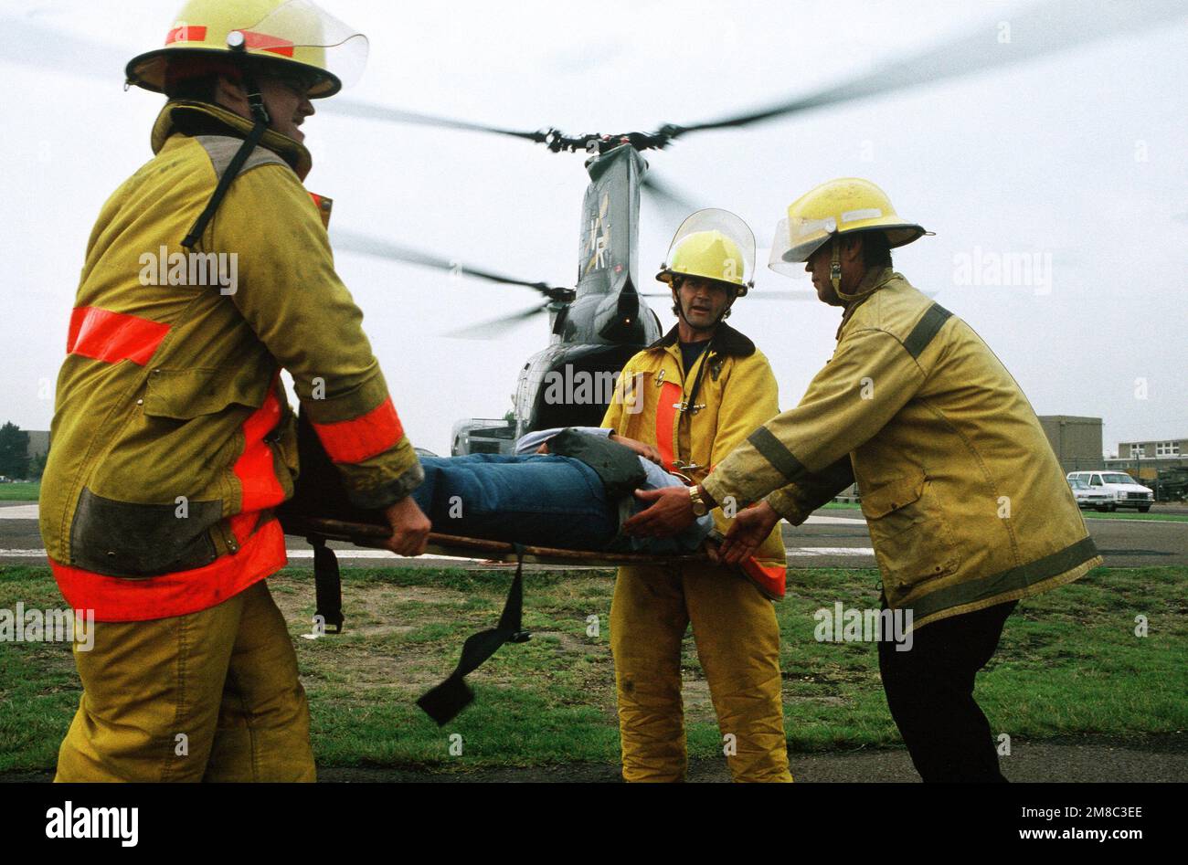 I vigili del fuoco sollevano un incidente simulato su una lettiera prima di caricarlo a bordo di un elicottero da combattimento Squadron 11 (HC-11) UH-46 Sea Knight Helicopter durante un esercizio di evacuazione medica, parte del PACEX '89. Subject Operation/Series: PACEX '89 base: Naval Amphibious base, Coronado Stato: California (CA) Paese: Stati Uniti d'America (USA) Foto Stock