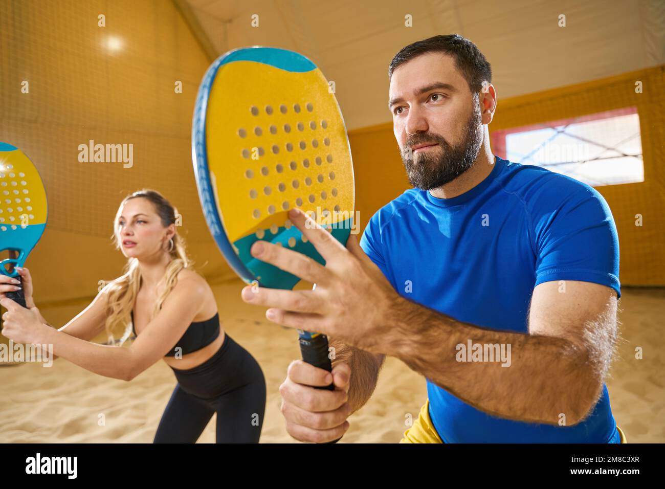 Uomo e donna in posa sportiva statica con racchette Foto Stock
