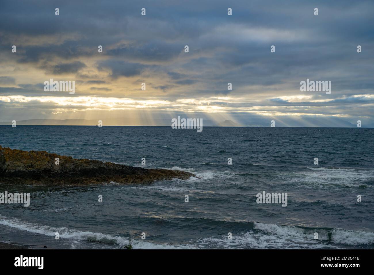 Il sole si irradia da dietro le nuvole sopra l'isola di Arran nel Firth di Clyde, da Dunure Ayrshire Scozia Foto Stock