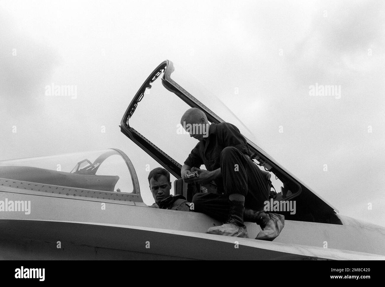 PFC Gary Henson aiuta il CPT Benjamin Cunningham ad allacciarsi nell'abitacolo di un F/A-18A Hornet durante l'esercizio combinato thailandese/statunitense Thalay Thai '89. Entrambi i Marines sono membri del Marine Fighter Attack Squadron 115 (VMFA-115). Paese: Thailandia (THA) Foto Stock