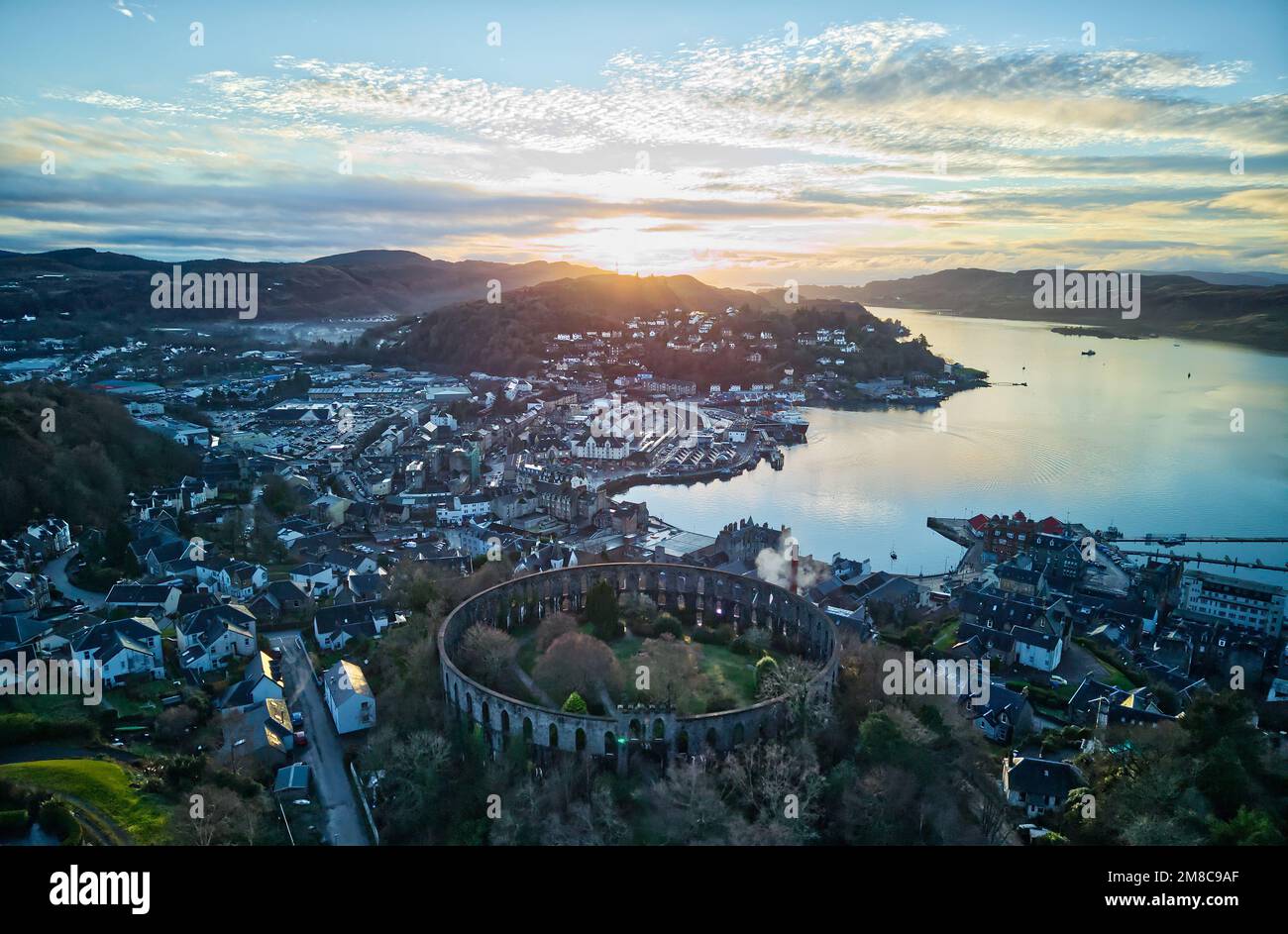 Vista su Oban e Oban Bay, McCaig's Tower in primo piano, Argyll, Scozia al tramonto Foto Stock