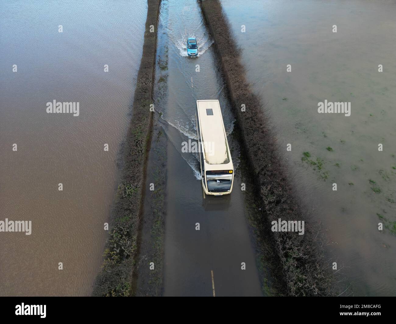 Sutton St Nicholas, Herefordshire, Regno Unito – Venerdì 13th gennaio 2023 – UK Weather – veduta aerea di un autobus che attraversa le acque alluvionali dal vicino fiume Lugg su una strada rurale tra Sutton St Nicholas e Hereford. Dopo giorni di pioggia, fiumi locali come il fiume Lugg, il fiume Teme e il fiume Wye sono tutti a livelli molto alti. Più previsioni di pioggia. Foto Steven Maggio / Alamy Live News Foto Stock