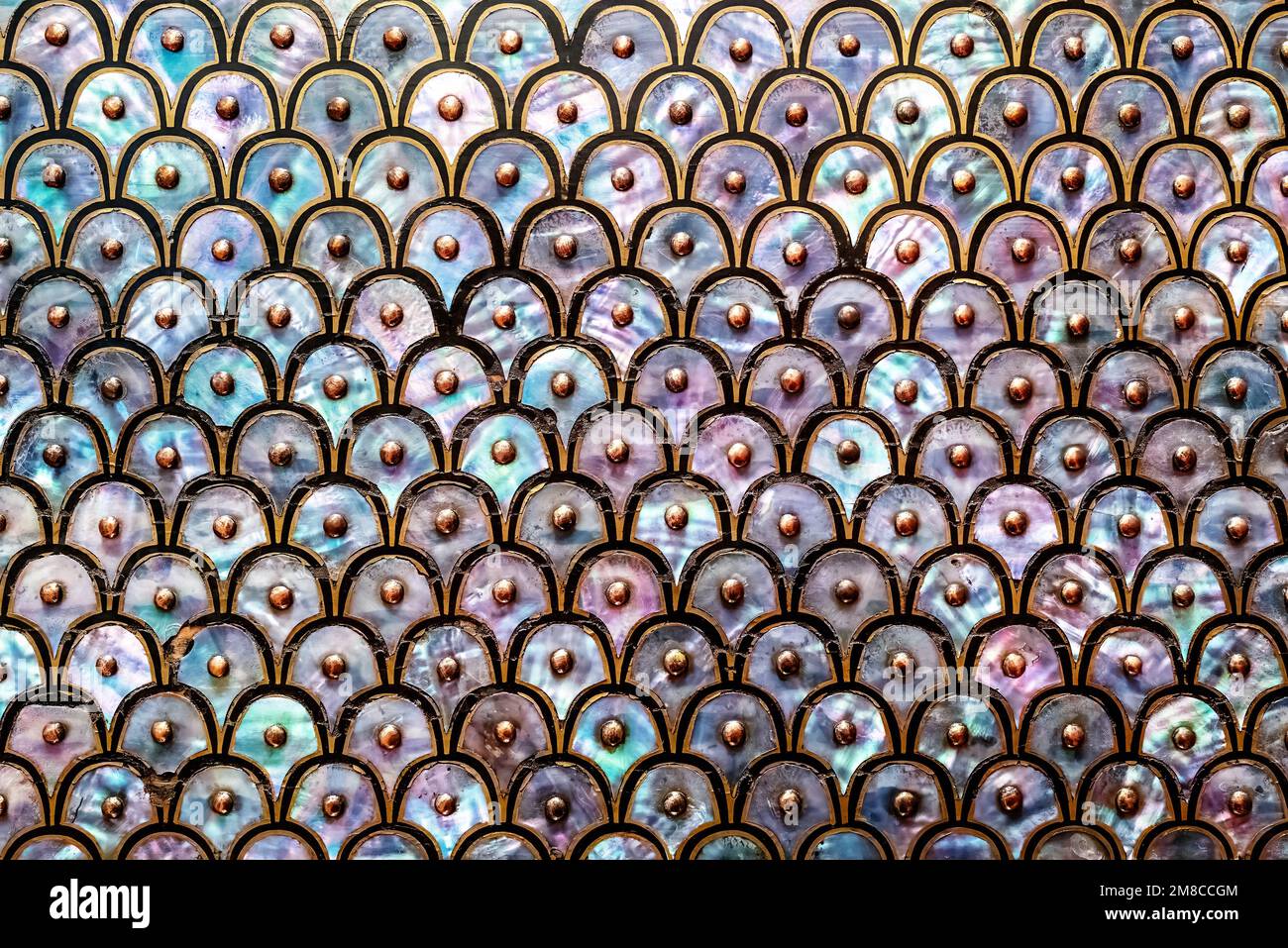 Sfondo astratto della madreperla. Design circolare e sovrapposto di conchiglia in nacre o abalone, con disegno nero e oro e borchie. Foto Stock