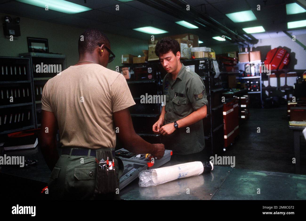 SENIOR AIRMAN Kenneth Morris, a sinistra, un elettricista di aeromobili, firma un multimetro digitale da AIRMAN 1st Classe Gary W. Walker, uno specialista di avionica dalla 18th Tactical Fighter Wing, durante l'esercizio COPE THUNDER 89-5. Soggetto operativo/Serie: COPE THUNDER 89-5 base: Clark Air base Stato: Luzon Paese: Filippine (PHL) Foto Stock