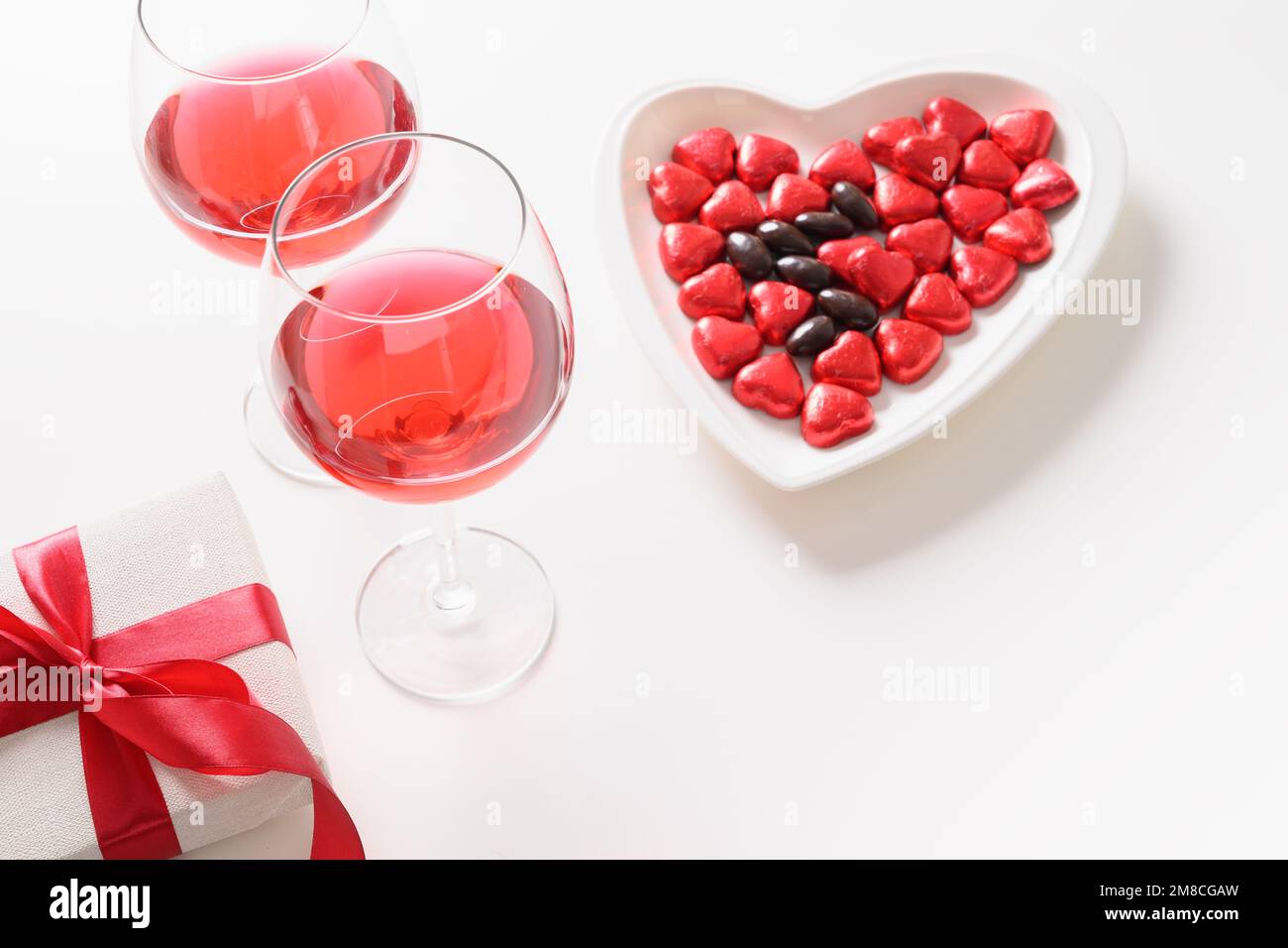 Incontri romantici, San Valentino con regalo, vino rosso, dolci al  cioccolato come cuore su sfondo bianco. Primo piano. Spazio di copia.  Sorpresa per gli uomini o per lui Foto stock - Alamy