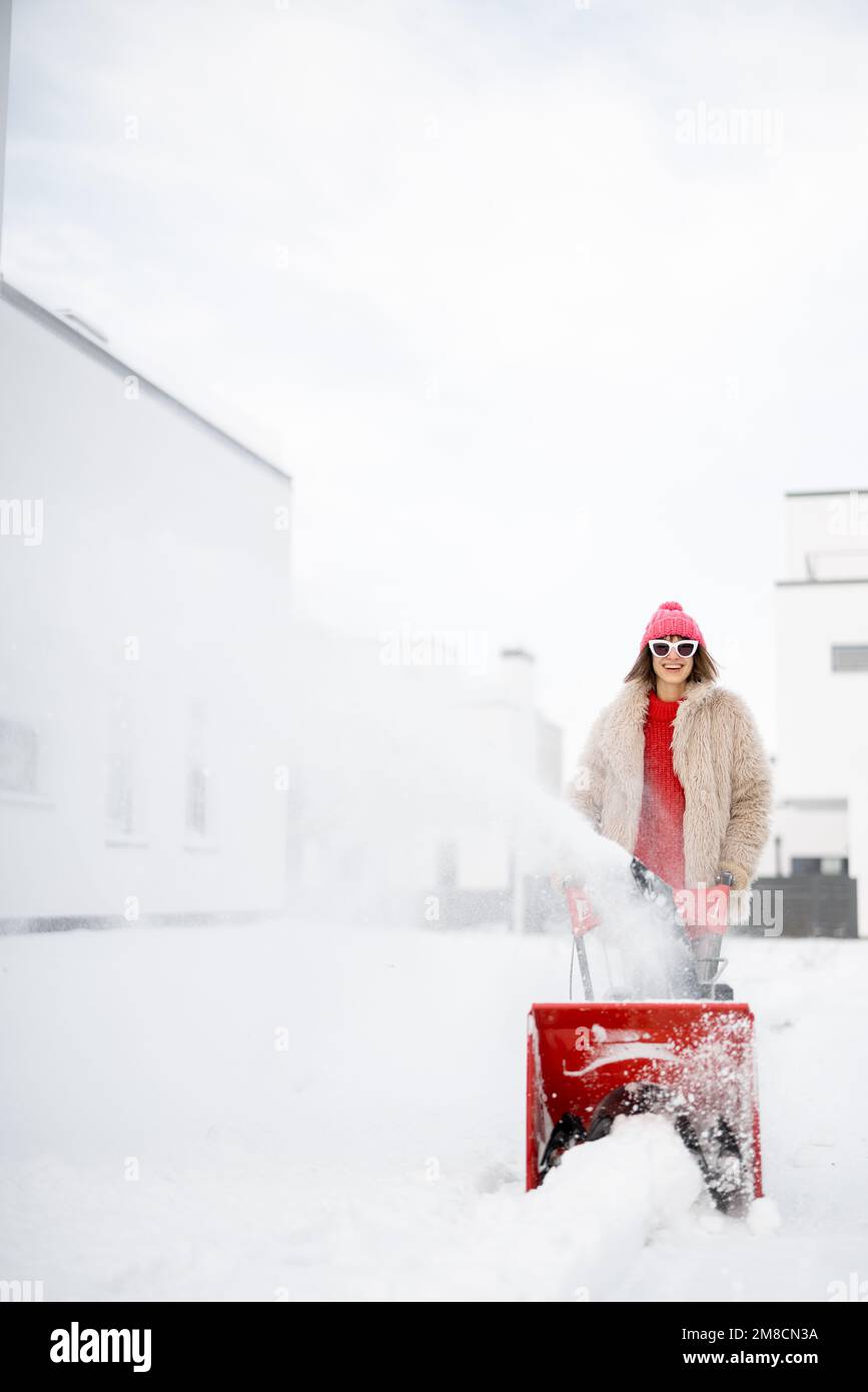 Donna rimuove la neve con un lancianeve vicino casa Foto Stock