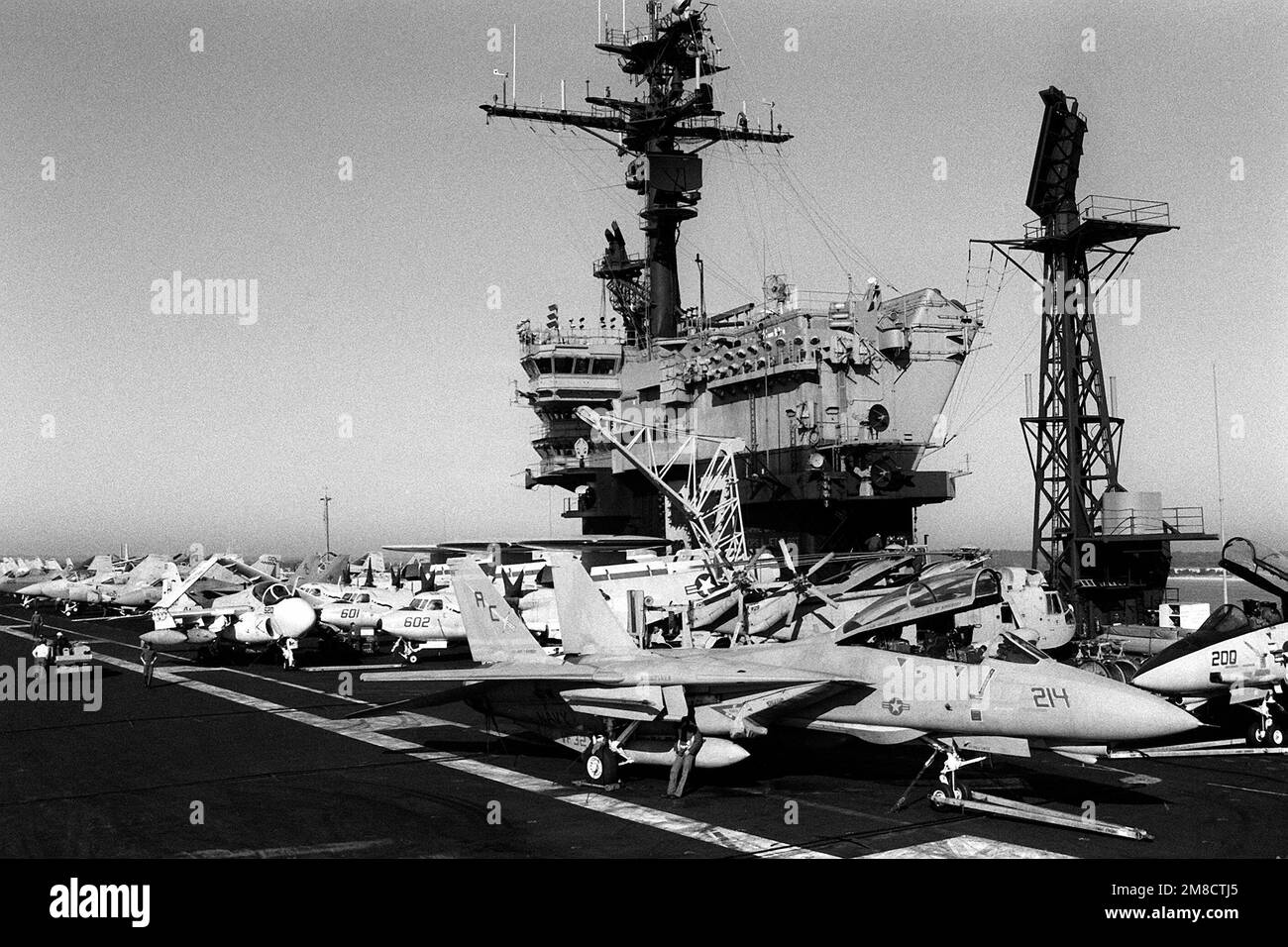 Gli equipaggi della piattaforma di volo effettuano operazioni vicino all'isola della portaerei USS JOHN F. KENNEDY (CV-67) durante la flotta ex 1-90. In primo piano è un F-14A Tomcat Aircraft of Fighter Squadron 32 (VF-32). Oggetto/Serie: FLOTTA EX 1-90 Paese: Oceano Atlantico (AOC) Foto Stock