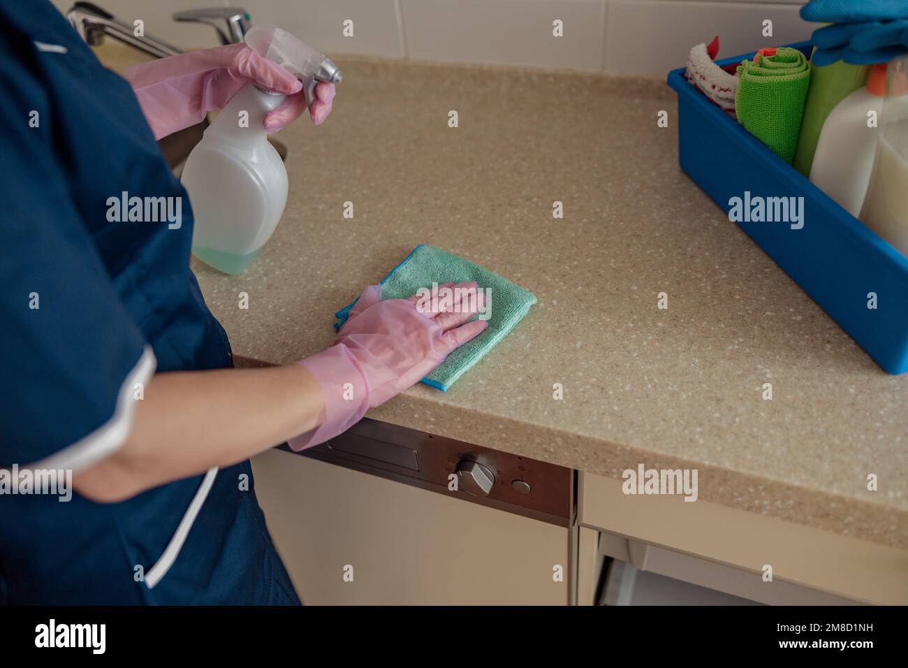 La cameriera nei guanti protettivi pulisce il piano di lavoro utilizzare straccio e detergenti efficaci in cucina Foto Stock