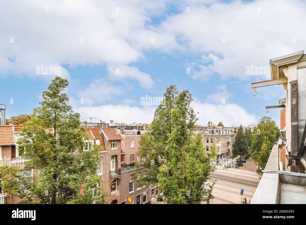 la vista da un appartamento ad amsterdam, con alberi ed edifici su entrambi i lati della strada c'è un cielo blu luminoso sopra Foto Stock